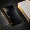 画面が割れたスマートフォンと新品の箱と保護ガラスフィルム